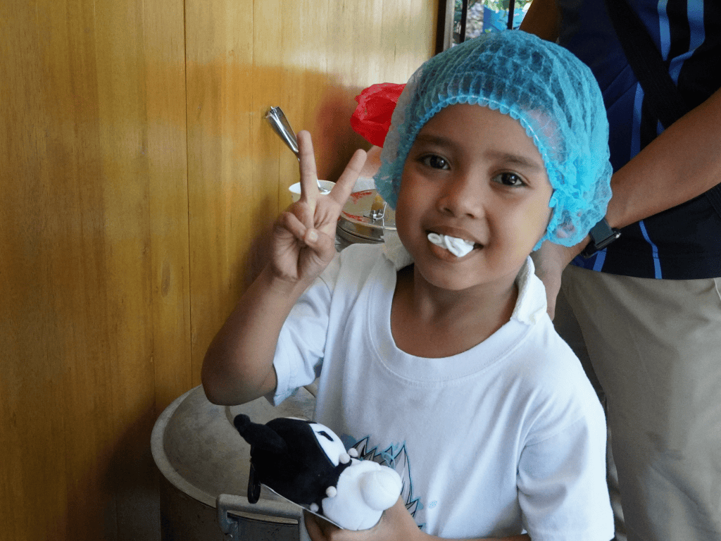 A young child who just recieved their dental treatment holding a stuffed animal and making a peace-sign gesture with their hands